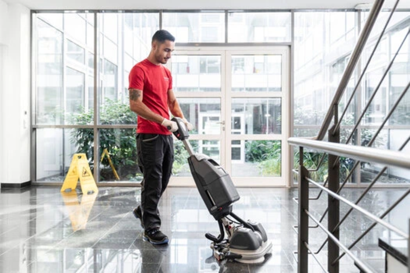 Dussmann Mitarbeiter reinigt mit Maschine den Boden.
