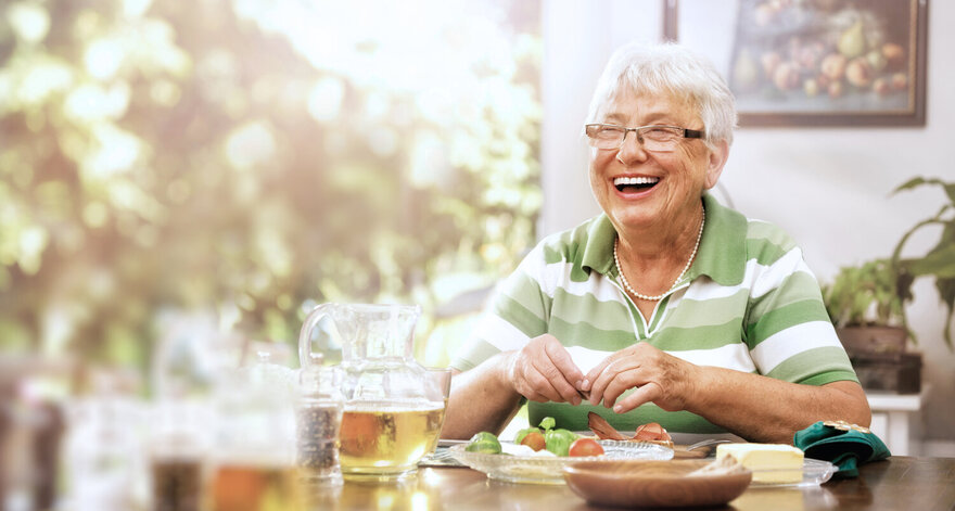 Lächelnde Seniorin isst Brotzeit