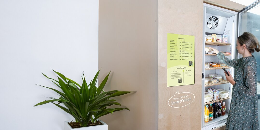 Frau nimmt in einem Büro einen Snack aus dem Smartfridge 